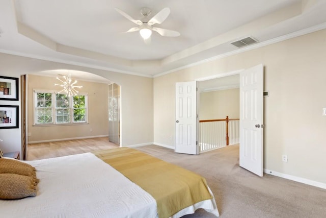 bedroom with crown molding, a tray ceiling, ceiling fan with notable chandelier, and carpet