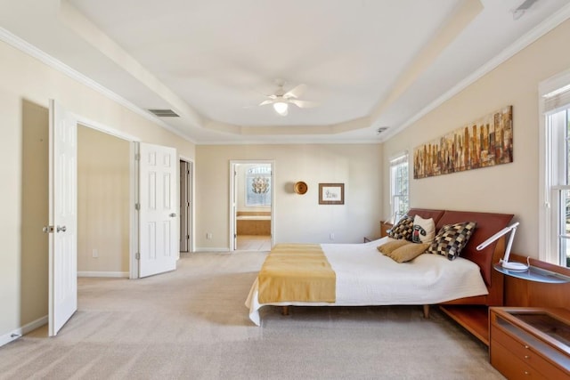 carpeted bedroom featuring a raised ceiling, ornamental molding, ensuite bathroom, and ceiling fan