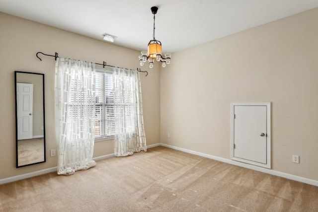 carpeted spare room featuring an inviting chandelier