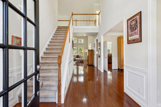 entryway with french doors, ornamental molding, dark wood-type flooring, and a high ceiling