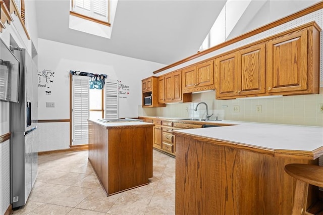 1732 Winding Woods Ln, Jonesboro, GA 30236 - kitchen featuring a skylight, brown cabinets, a center island, light countertops, and a wainscoted wall