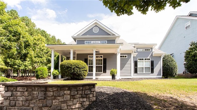 rear view of property featuring ceiling fan, a porch, and a lawn