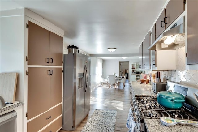 kitchen with stainless steel appliances, light wood-type flooring, and backsplash