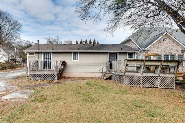 rear view of property featuring a wooden deck and a lawn