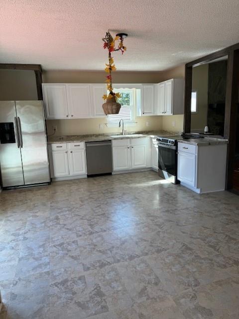 kitchen featuring appliances with stainless steel finishes, a textured ceiling, and white cabinetry