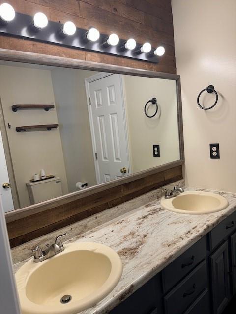 bathroom with double vanity, a sink, and toilet