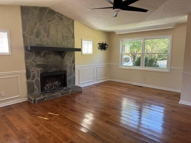 unfurnished living room featuring a fireplace, a wainscoted wall, a ceiling fan, wood finished floors, and vaulted ceiling