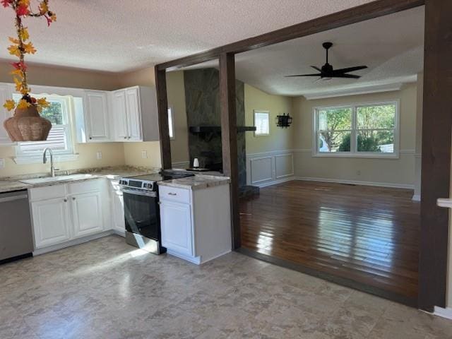kitchen with white cabinets, stainless steel appliances, open floor plan, and a sink