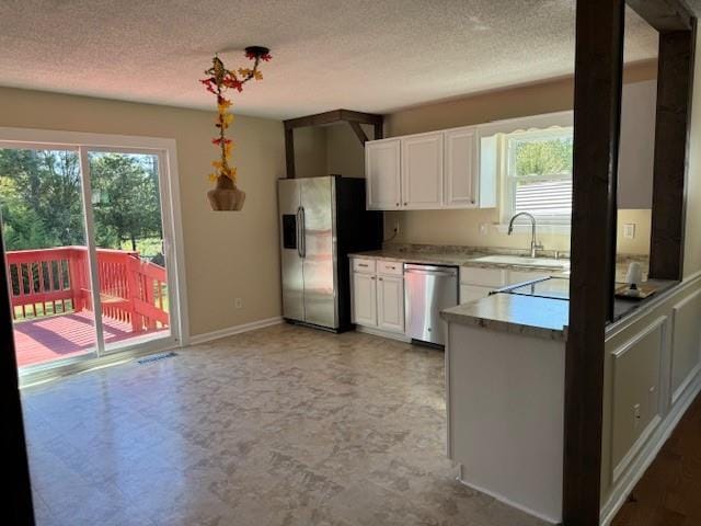 kitchen with plenty of natural light, stainless steel appliances, a textured ceiling, and white cabinets