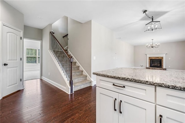 399 Cobblestone Trl, Dallas, GA 30132 - kitchen with an inviting chandelier, dark wood finished floors, light stone countertops, white cabinets, and baseboards