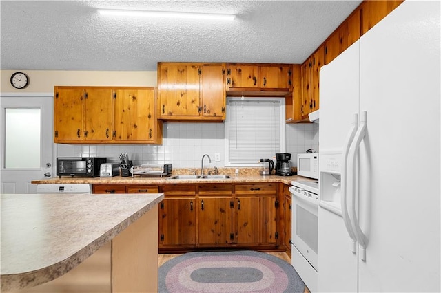 kitchen featuring white appliances, decorative backsplash, brown cabinetry, light countertops, and a sink