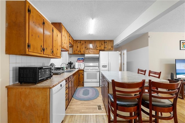 kitchen featuring light countertops, white appliances, light wood-type flooring, and tasteful backsplash