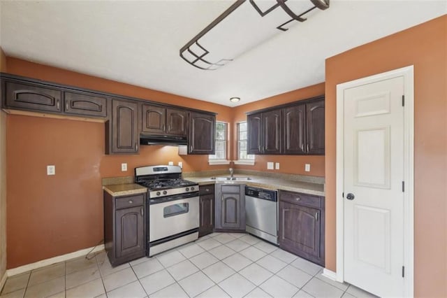 kitchen with stainless steel appliances, sink, dark brown cabinets, and light tile patterned floors