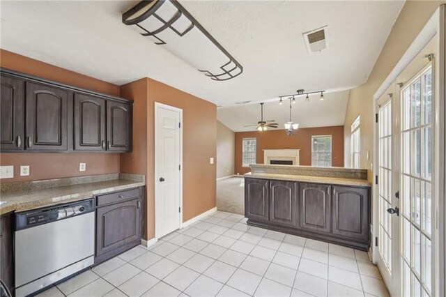 kitchen featuring light tile patterned flooring, lofted ceiling, hanging light fixtures, stainless steel dishwasher, and dark brown cabinetry