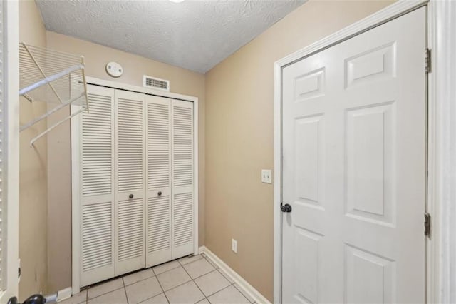 unfurnished bedroom featuring a textured ceiling, a closet, and light tile patterned floors