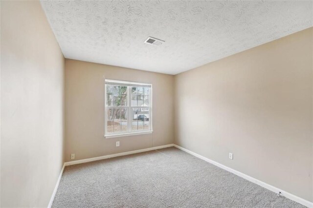 empty room with carpet and a textured ceiling