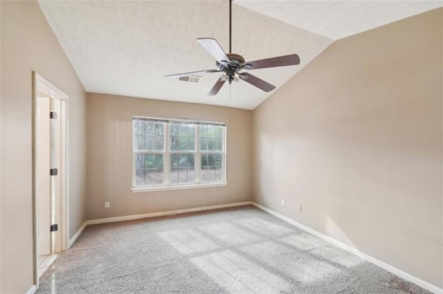 spare room with ceiling fan, vaulted ceiling, light carpet, and a textured ceiling