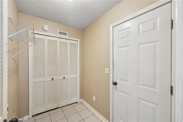 unfurnished bedroom with light tile patterned floors, a textured ceiling, and a closet