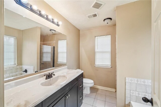 bathroom with a washtub, vanity, tile patterned floors, and toilet