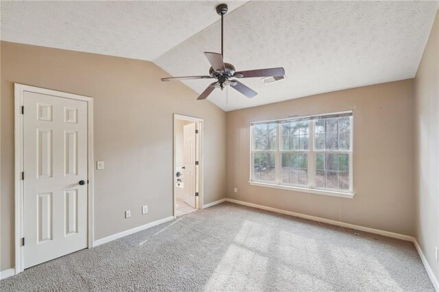 empty room with ceiling fan, vaulted ceiling, light colored carpet, and a textured ceiling