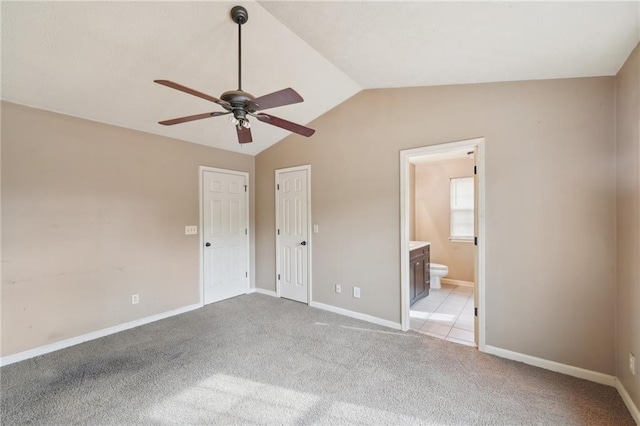 unfurnished bedroom featuring light carpet, connected bathroom, and vaulted ceiling