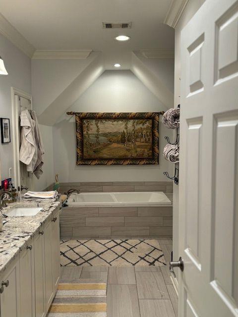 bathroom with tiled tub and vanity