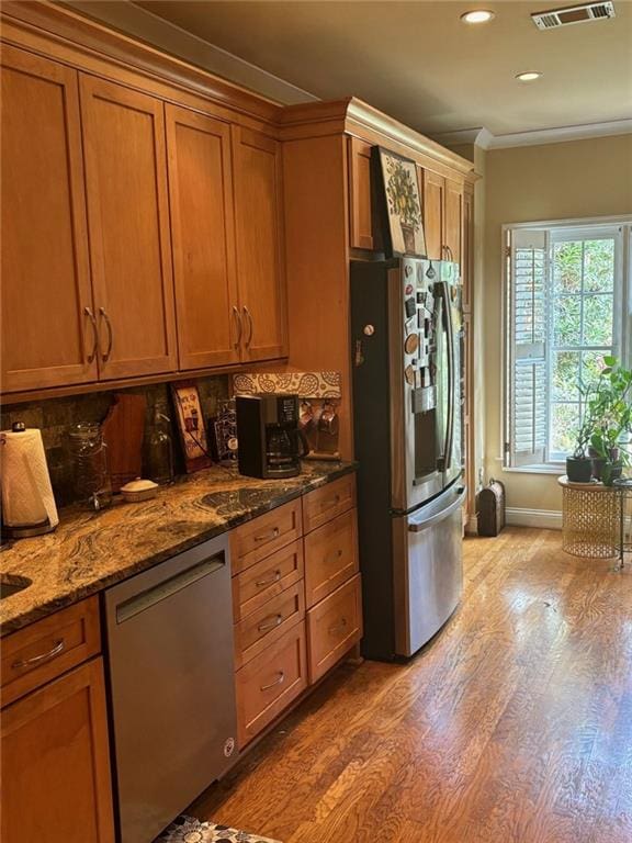 kitchen with light stone countertops, wall chimney range hood, dark hardwood / wood-style flooring, backsplash, and stainless steel gas stovetop