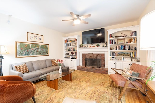 living room featuring ceiling fan, a brick fireplace, and wood finished floors