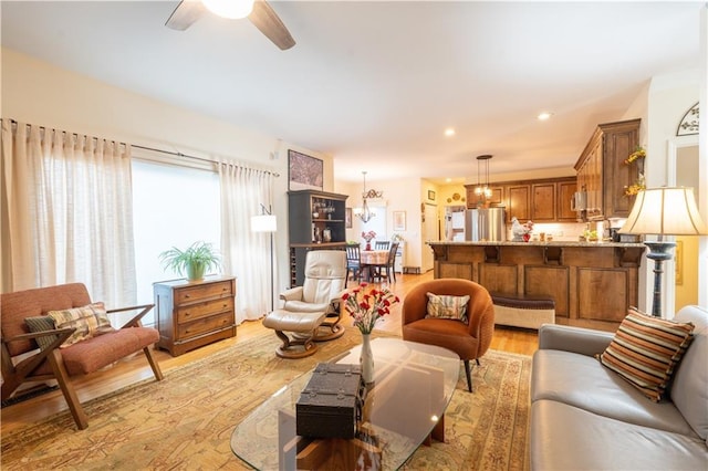 living room with light wood-type flooring, a ceiling fan, a chandelier, and recessed lighting