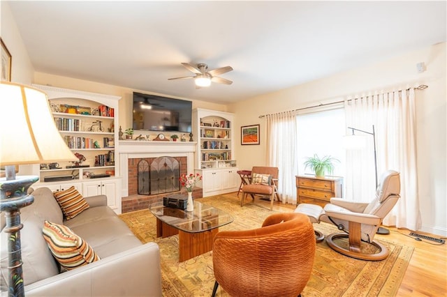 living room with ceiling fan, light wood-style flooring, and a fireplace