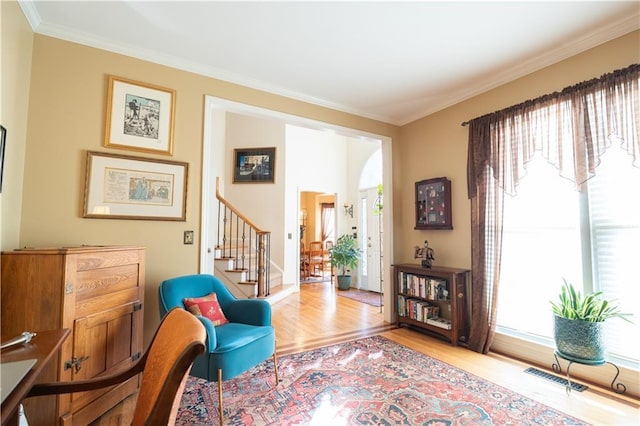 sitting room featuring wood finished floors, crown molding, stairway, and baseboards