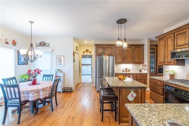 kitchen with stainless steel appliances, brown cabinets, light stone countertops, and backsplash