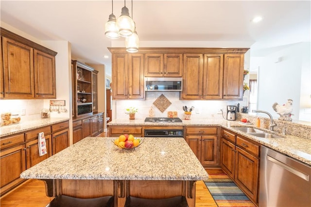 kitchen with appliances with stainless steel finishes, a sink, brown cabinetry, a kitchen breakfast bar, and recessed lighting