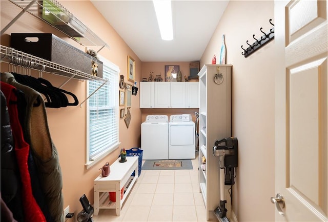 washroom with washer and clothes dryer, light tile patterned floors, and cabinet space