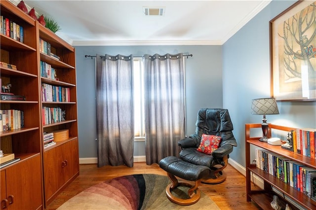 living area with ornamental molding, wood finished floors, and baseboards