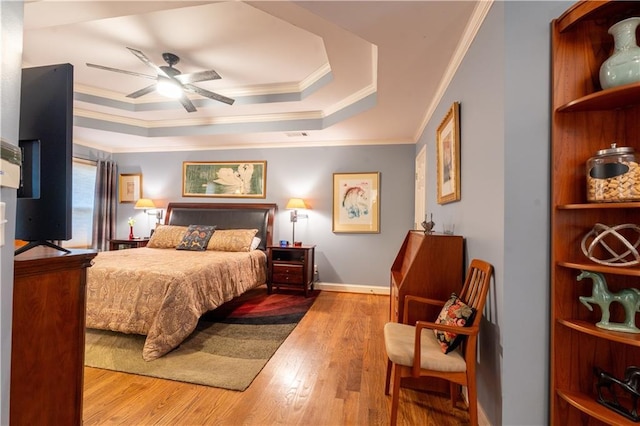 bedroom with a raised ceiling, ornamental molding, and wood finished floors