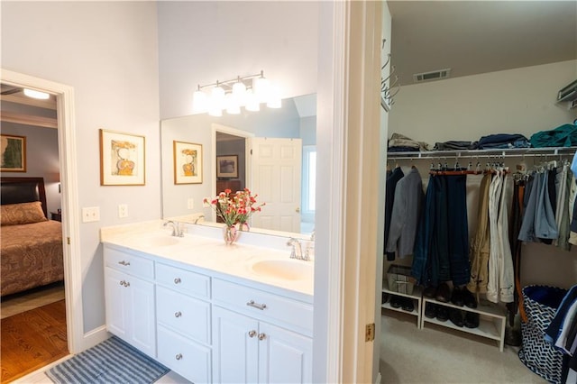ensuite bathroom with double vanity and a spacious closet