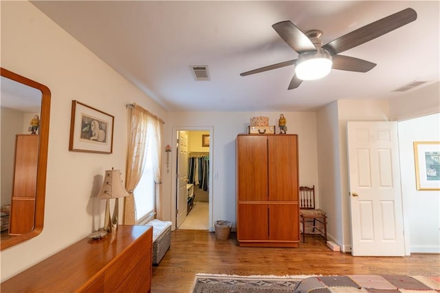 bedroom with wood finished floors, a spacious closet, and a ceiling fan