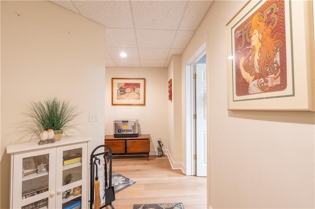 hall featuring a paneled ceiling, light wood finished floors, and recessed lighting