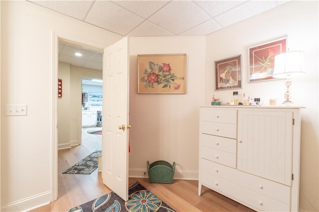 bedroom featuring a drop ceiling, light wood-style flooring, and baseboards