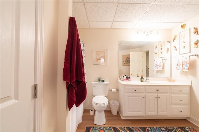 bathroom featuring wood finished floors, toilet, vanity, and a paneled ceiling