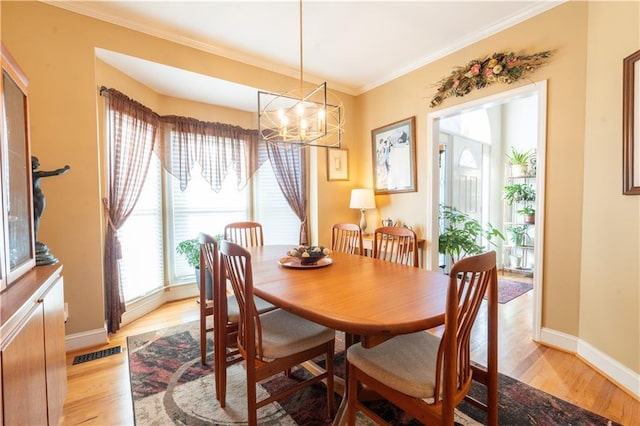 dining space with a chandelier, light wood-style floors, crown molding, and baseboards