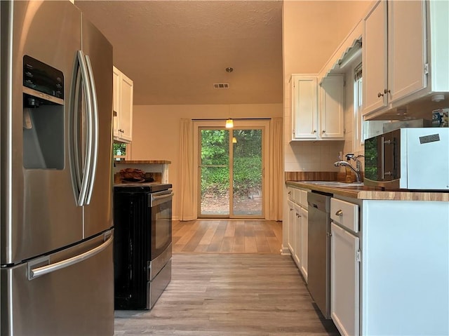 225 Magnolia Tree Ct, Johns Creek, GA 30022 - kitchen with stainless steel appliances, light wood-type flooring, white cabinetry, decorative backsplash, and a sink