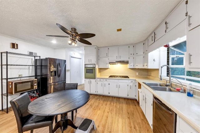 kitchen featuring sink, white cabinetry, light hardwood / wood-style flooring, a textured ceiling, and appliances with stainless steel finishes