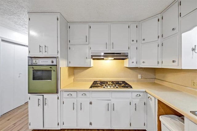 kitchen featuring white cabinetry, oven, stainless steel gas cooktop, and a textured ceiling