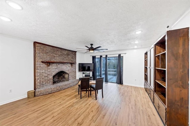 living room featuring ceiling fan, light hardwood / wood-style floors, a brick fireplace, and a textured ceiling