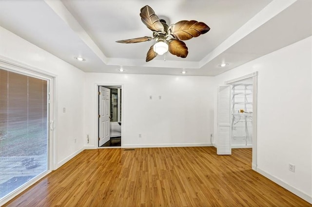 spare room with ceiling fan, a raised ceiling, and light hardwood / wood-style flooring