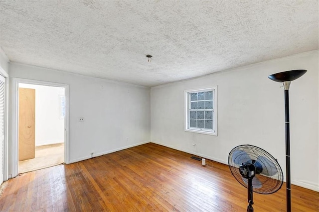 unfurnished room with hardwood / wood-style floors and a textured ceiling