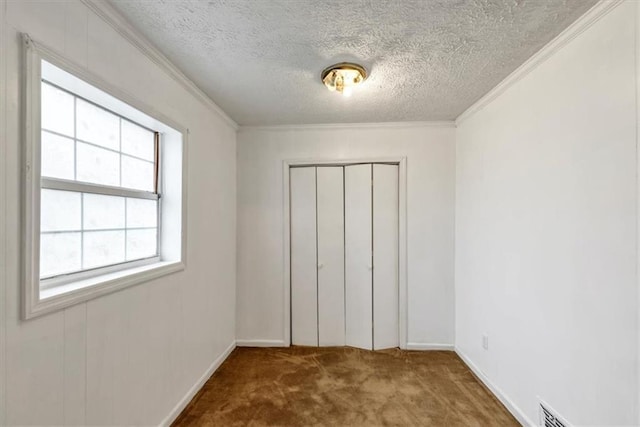 unfurnished bedroom featuring ornamental molding, carpet, a textured ceiling, and a closet