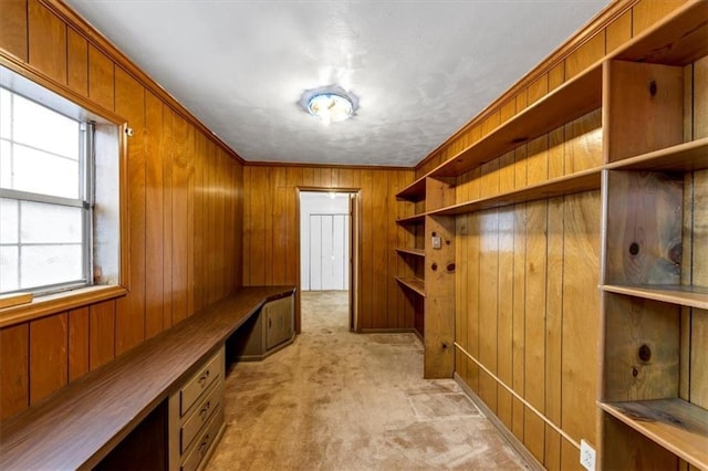 mudroom featuring built in desk, light carpet, and wooden walls